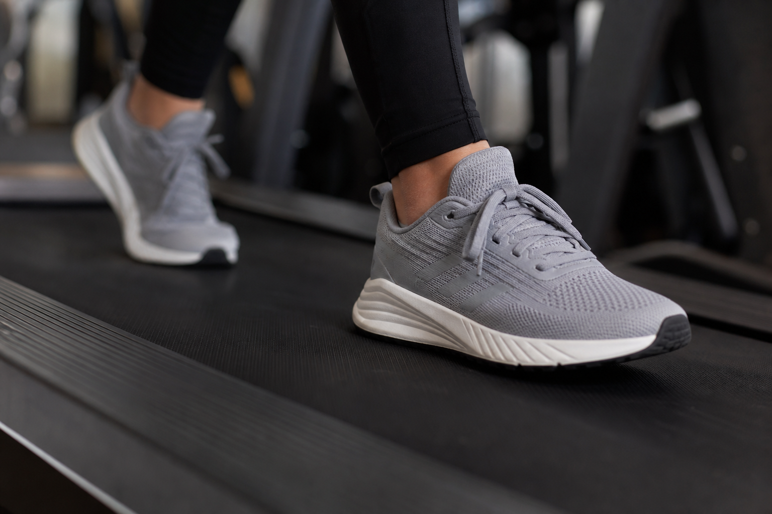 Close-up of feet in running shoes on a treadmill belt