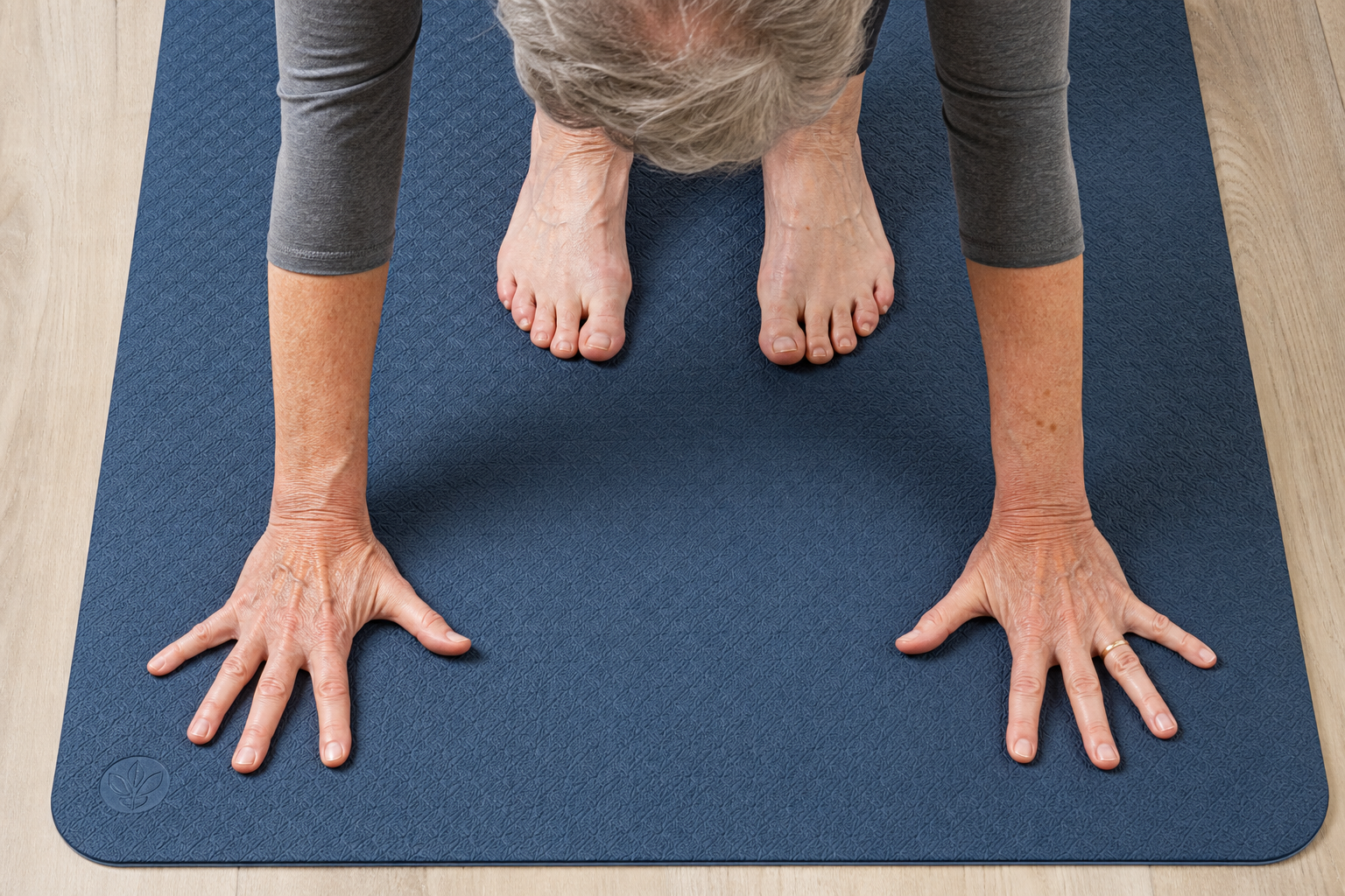 Close-up of hands and feet gripping a textured non-slip yoga mat surface