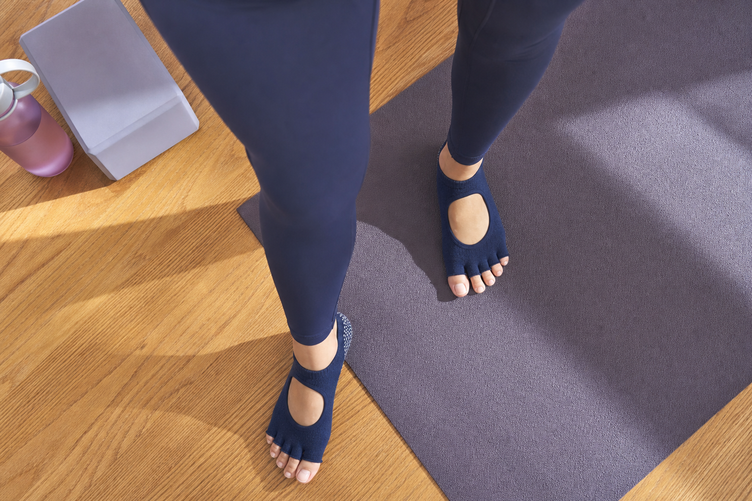 Overhead view of feet in grip socks on exercise mat and hardwood floor during home workout
