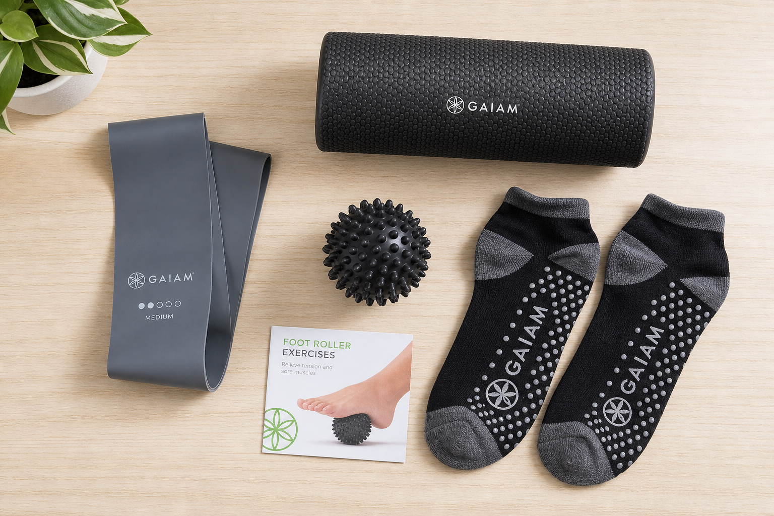 Flat lay of foot care and exercise equipment including foam roller, resistance band, and grip socks