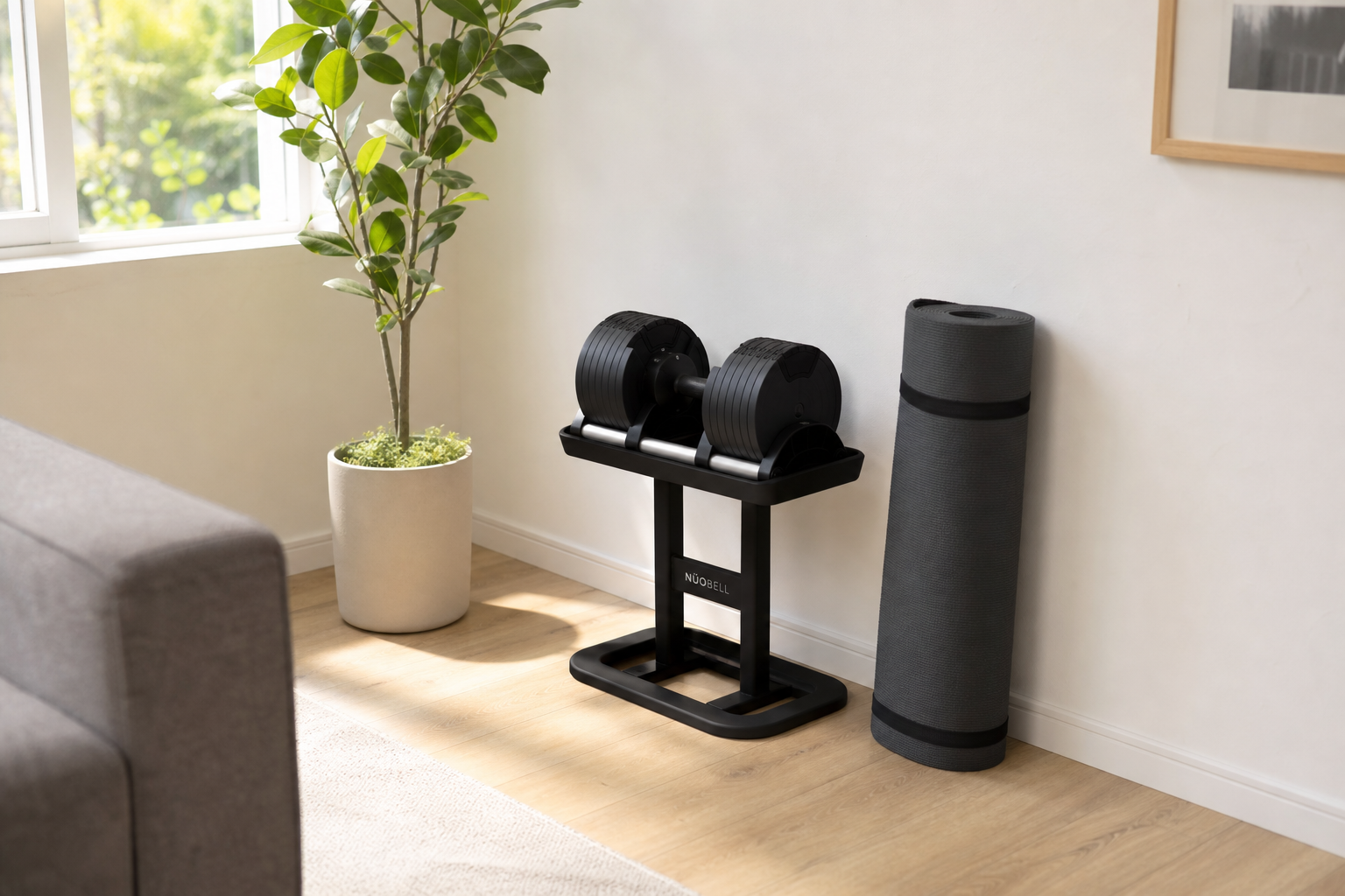 Compact adjustable dumbbell set on a small tray stand in the corner of a tidy, space-efficient home room
