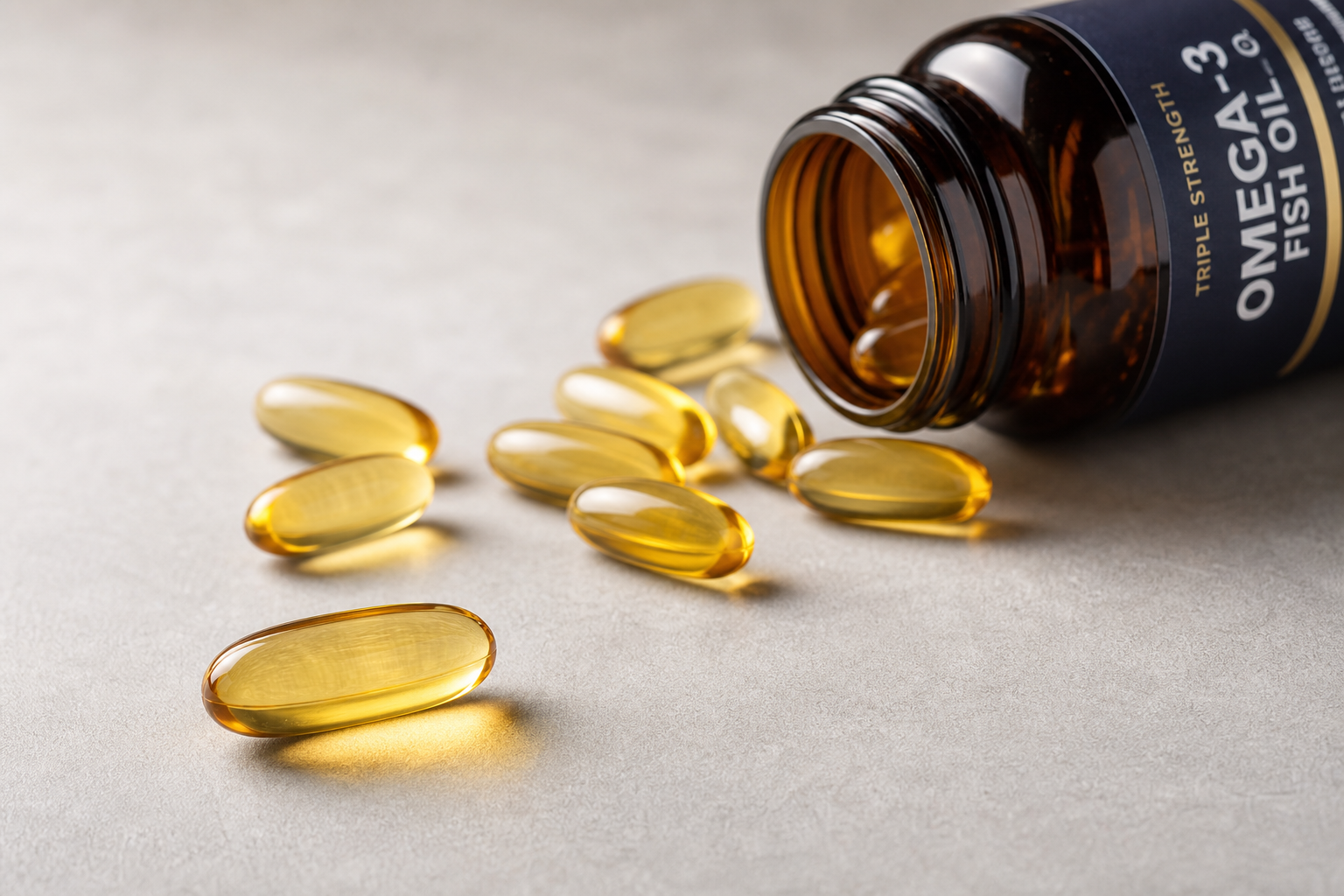 Close-up of amber omega-3 fish oil supplement capsules arranged on a gray surface with a dark glass bottle
