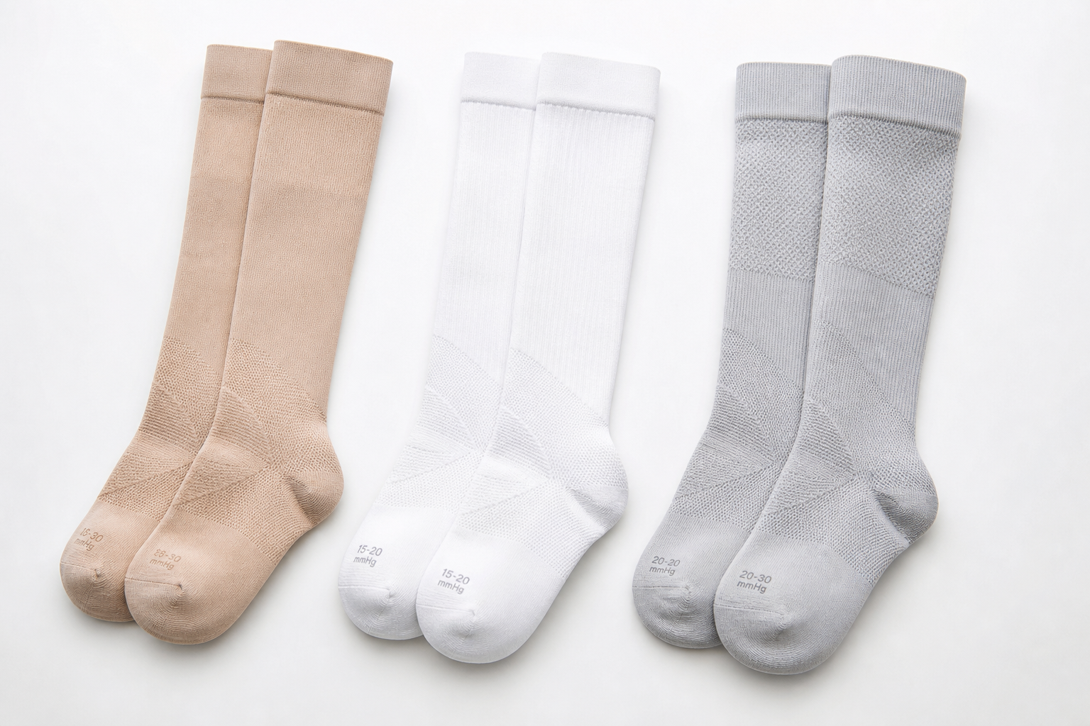 Three compression socks with different compression levels arranged side by side on a white surface