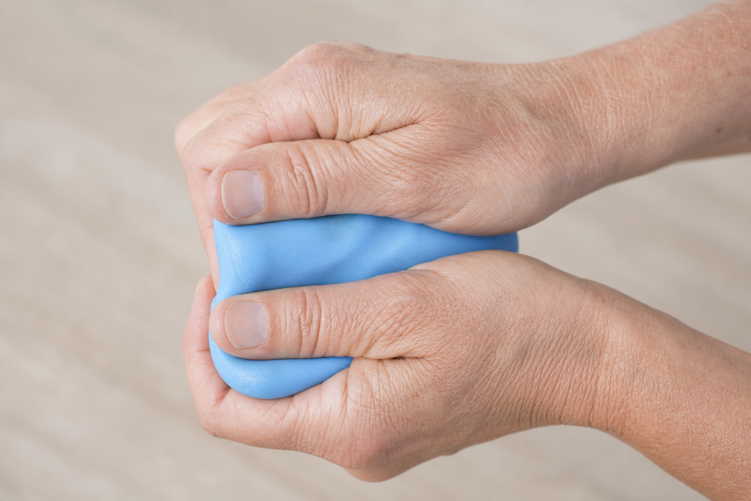 Hands squeezing blue therapy putty as a hand exercise for arthritis and dexterity